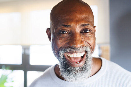 Close-up portrait of cheerful bald african american senior man laughing in log cabin