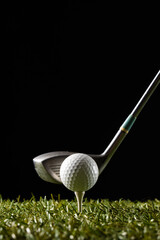 White golf ball on golf tee and golf club on grass with copy space