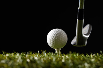 White golf ball on golf tee and golf club on grass with copy space