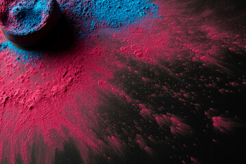 High angle view of multi coloured powder and bowl with copy space on black background
