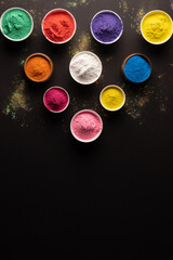 Close up of multi coloured powder in bowls with copy space on black background
