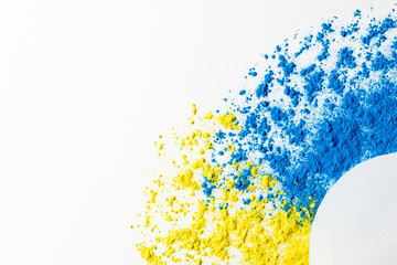 Close up of blue and yellow coloured powder and white circle with copy space on white background