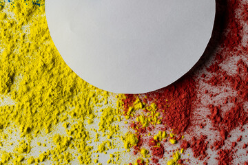 Close up of red and yellow coloured powder and white circle with copy space on white background
