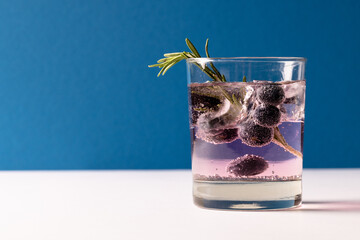 Glass with water and berry on white and blue background