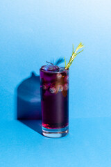 Vertical image of glass with drink and berry on blue background