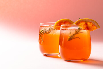 Glasses with drinks and fruits over pink background