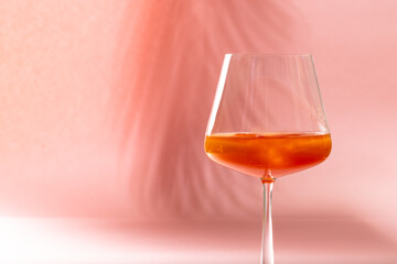 Glass with drink over pale pink background with shadows