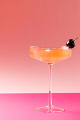 Vertical image of glass with drink and fruits over pink background