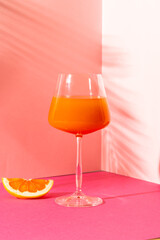 Vertical image of orange juice in pink space with shadows