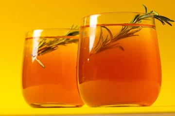 Fotobehang Glasses with drinks and thyme over yellow background © vectorfusionart