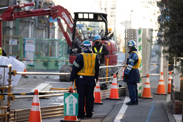 工事現場の歩行者を誘導する黄色い反射ベストを着た誘導員