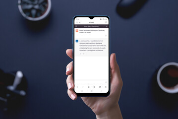 Artificial intelligence chat app on phone display in hand.  User asks the AI to write him a text about smartwatches