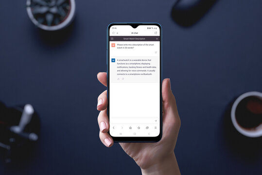 Artificial intelligence chat app on phone display in hand.  User asks the AI to write him a text about smartwatches