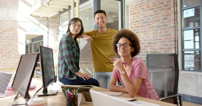 Group portrait of happy diverse male and female colleagues smiling in casual office, slow motion