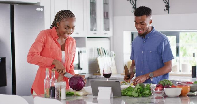 Happy african american couple preparing meal in kitchen