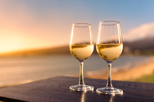 Romantic summertime lifestyle beach side getaway for two. Pair of wine glasses and tropical ocean view  - Powered by Adobe