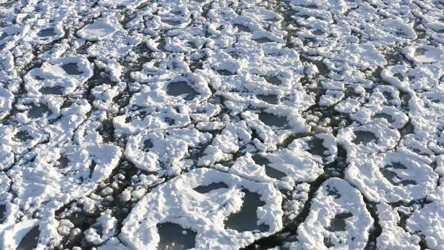 Aerial drone clip flying low above frozen ice and snow covering Lake Michigan.