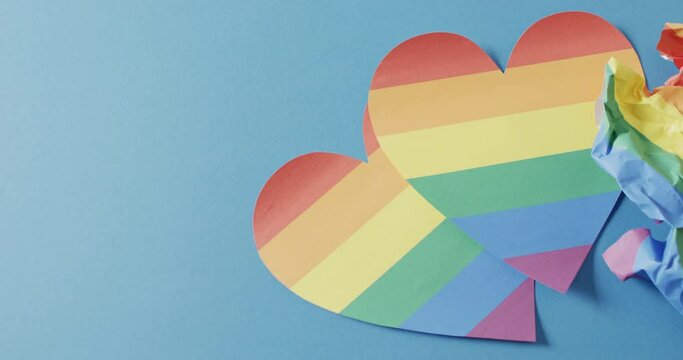 Video of rainbow hearts over blue background with copy space