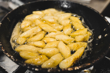 Roasting polish potato dumpling in butter in a frying pan. Polish cuisine side dish. Restaurant kitchen food preparation process. Horizontal indoor shot. High quality photo