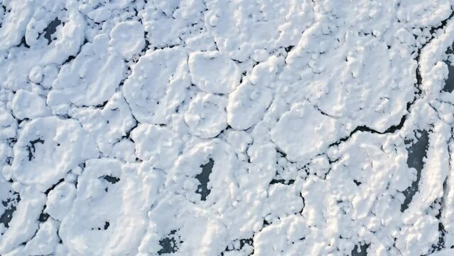 Lowering down aerial above scale-like Lake Michigan ice chunks encrusted in white snow from a polar vortex that moved through the Chicago region.