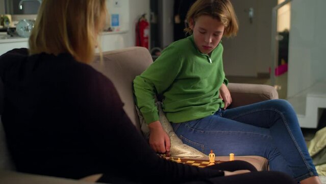 MS - Boy plays chess with his mother at home sitting on the sofa 3