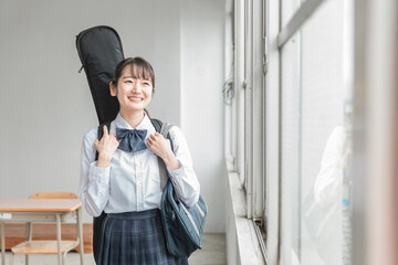 学校の教室で楽器・ギターを持った軽音部・吹奏楽部の高校生・中学生・女子高生（制服・バンド）
