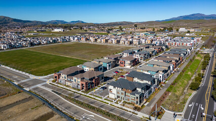 Aerial photos over apartments and houses in Dublin, California with a green field and solar panels