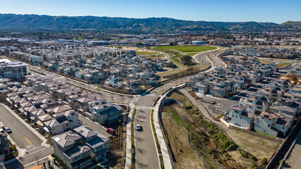 Aerial photos over apartments and houses in Dublin, California with a green field and solar panels