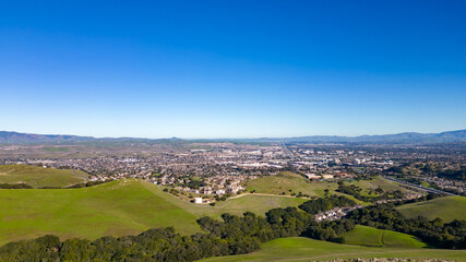 Naklejka premium Aerial photos over the Dublin Hills in Dublin, California with a city in the background with a blue sky