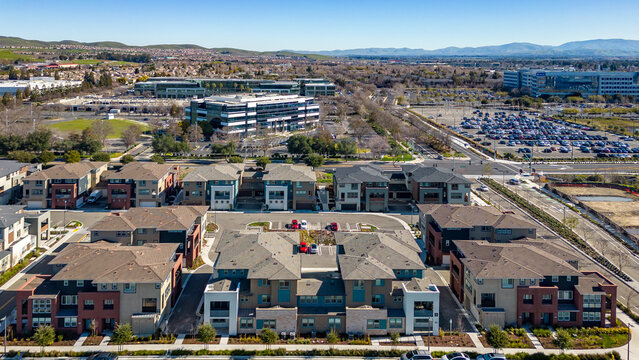 Aerial photos over apartments and houses in Dublin, California with a green field and solar panels