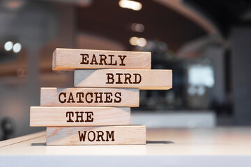 Wooden blocks with words 'Early bird catches the worm'.