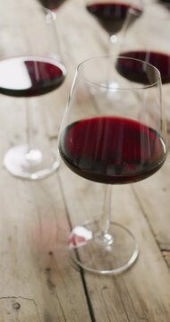 Vertcal video of res wine in glasses on wooden table