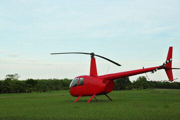 Fototapeta na wymiar Modern red helicopter on green grass outdoors