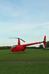 Fototapeta na wymiar Modern red helicopter on green grass outdoors