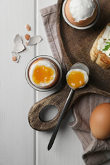 Breakfast with soft boiled eggs served on white wooden table, flat lay
