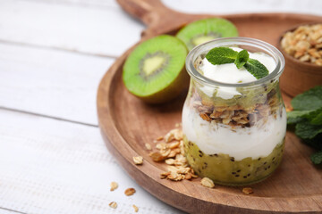 Delicious dessert with kiwi, yogurt and muesli on wooden board, closeup. Space for text