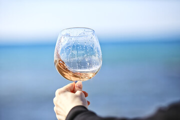 a glass of port wine on the background of the sea, a hand with wine