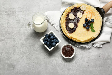 Delicious crepes with different products on light grey table, flat lay. Space for text