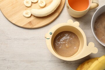 Baby food. Bowls with banana puree on light wooden table, flat lay and space for text