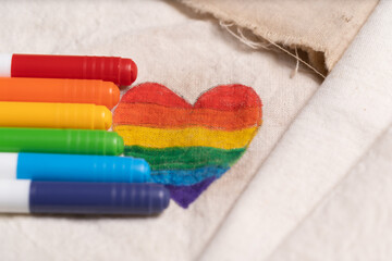 corazón de orgullo gay pintado sobre tela blanca con los plumones a un lado