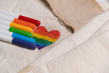 corazón de orgullo gay pintado sobre tela blanca con los plumones a un lado