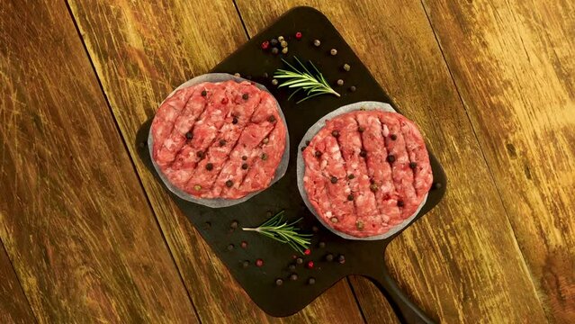 Raw meat burger cutlets, with spices and rosemary.