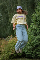 Portrait of a young beautiful girl in jeans and a T-shirt in a summer park.