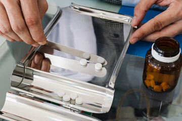 Closeup image hand of pharmacist counting and arrange pills on qualified stainless counting tray with spatula in pharmacy. Pharmacist prepare medication in stainless tray by prescription at drugstore.