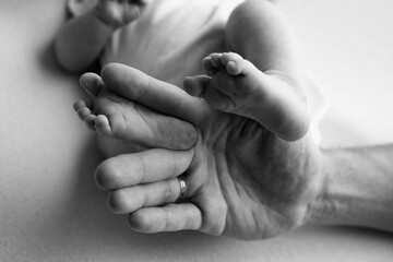 Baby feet in the hands of mother, father, older brother or sister, family.