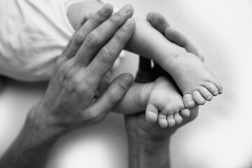 Baby feet in the hands of mother, father, older brother or sister, family. 