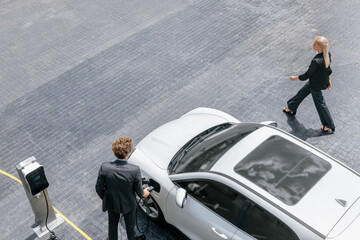 Aerial view progressive lifestyle of businesspeople with electric car connected to charging station...