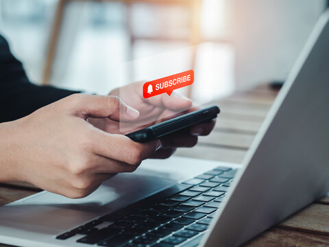 Subscription concept. Red subscribe button with bell icon appear on smart mobile phone in hands. Smartphone horizontal style holding by businesswoman who watching on entertainment applicatiion.