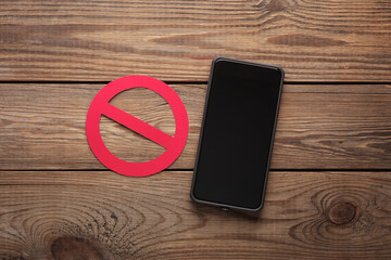 Smartphone with prohibition sign on a wooden table. Eco concept
