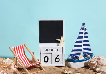 Beach holiday composition with sand, seashells, sailboat, deck chair and wooden block calendar with date august 06. Vacation, summertime, creative travel still life